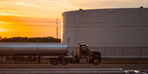 Truck driving on the highway with a sunset behind it