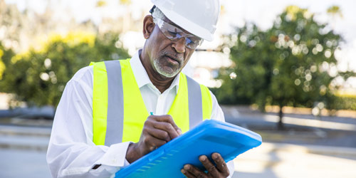 Person in a hard hat looking at a clipboard