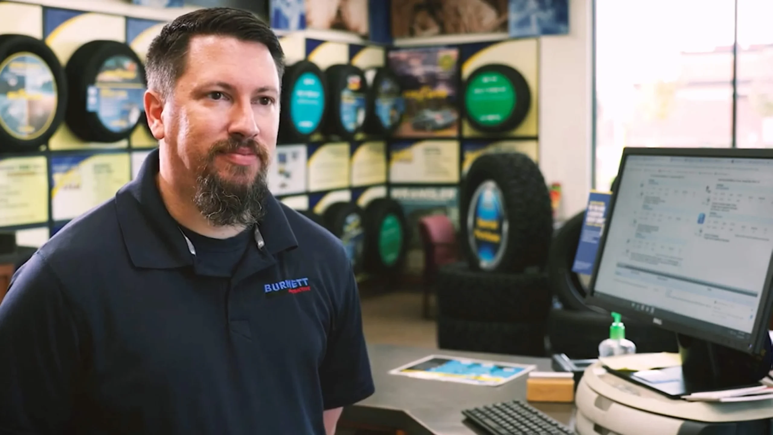 Tire technician standing in front of tire displays and workbench