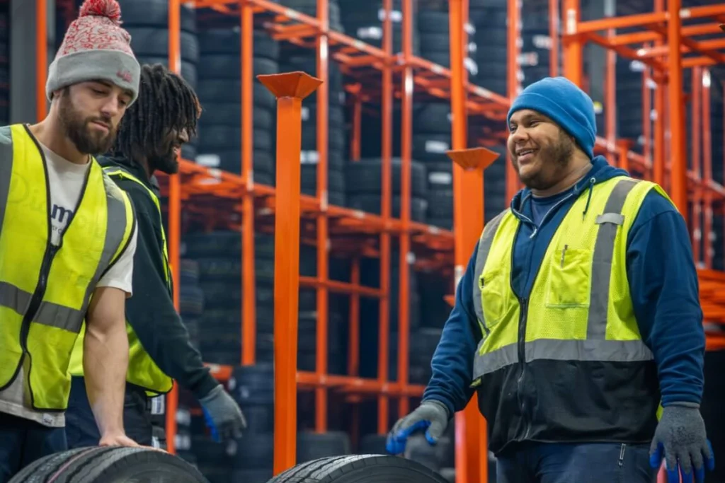 Warehouse employee working and laughing in distribution center with safety gear
