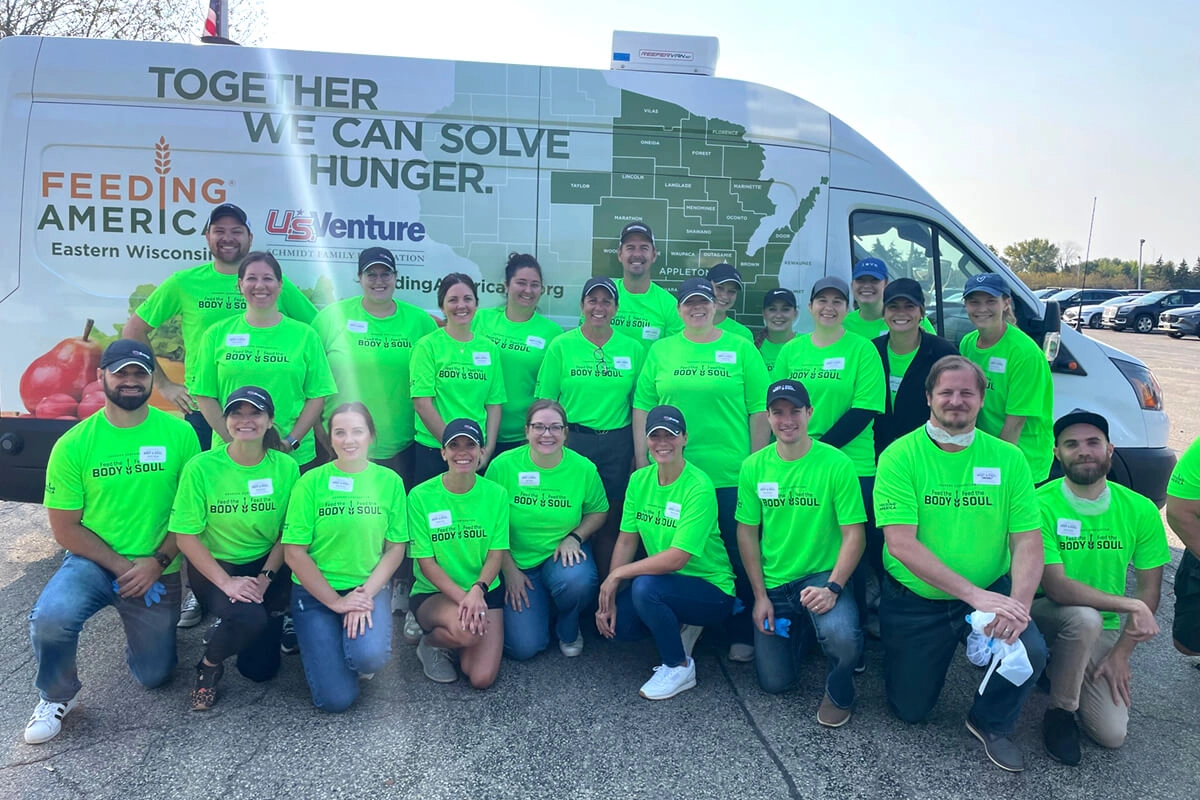 U.S. Venture volunteers in matching green shirts outside food bank vehicle
