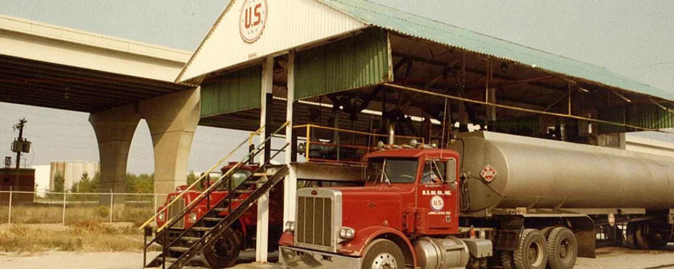 Historic delivery truck parked outside older distribution warehouse