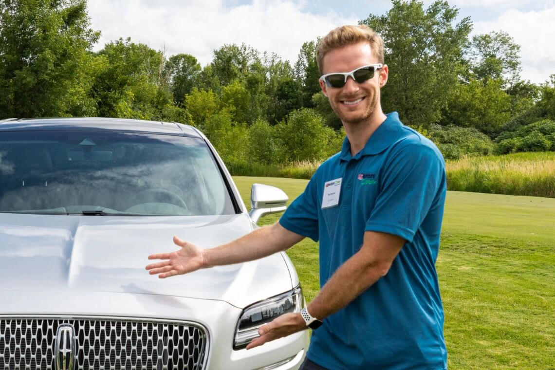 Employee showcasing Lincoln vehicle for community service initiative