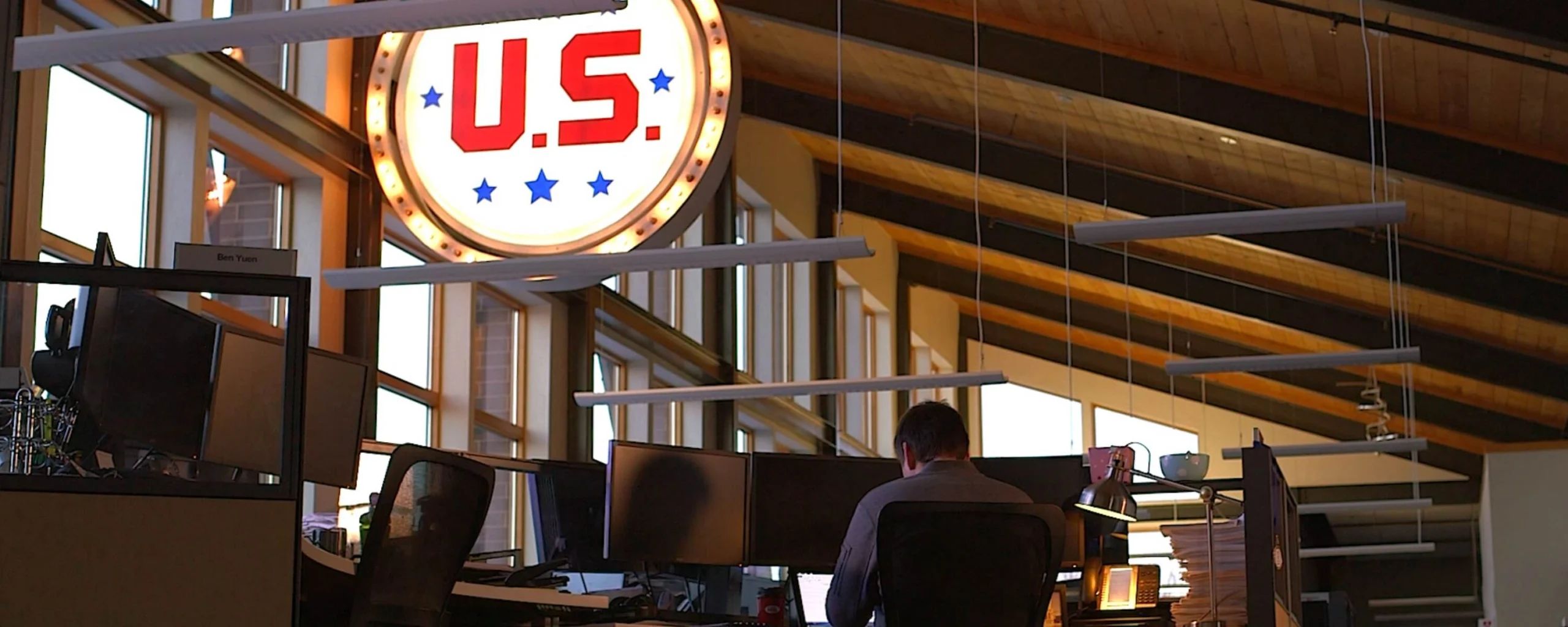 Man at computer inside U.S. Venture headquarters featuring branded signage