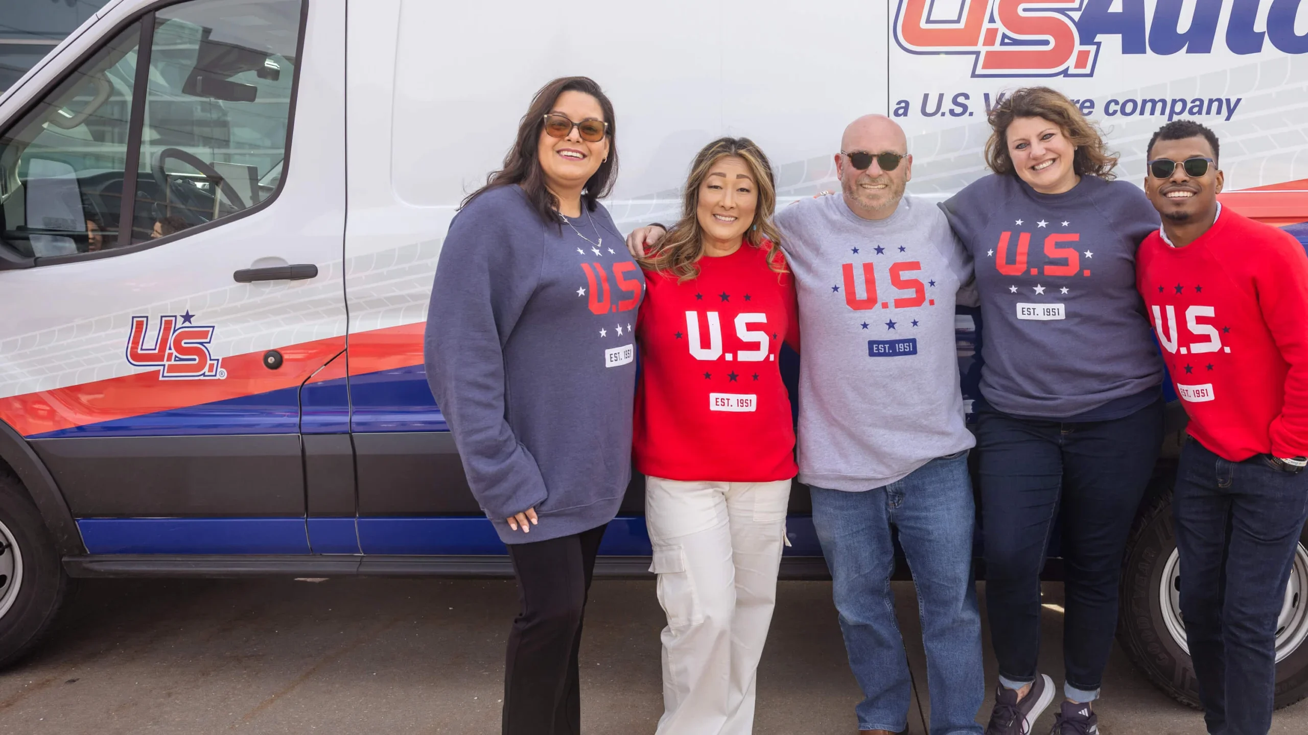 Employees wearing U.S. Venture sweatshirts posing outside U.S. AutoForce van